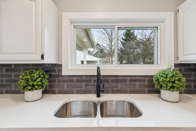 room details with decorative backsplash, sink, and white cabinetry