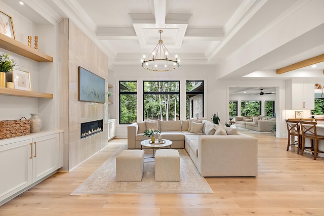 living room with ceiling fan with notable chandelier, a high end fireplace, light wood-type flooring, beam ceiling, and coffered ceiling