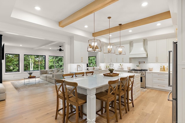 dining space featuring ceiling fan, sink, light hardwood / wood-style flooring, and beam ceiling