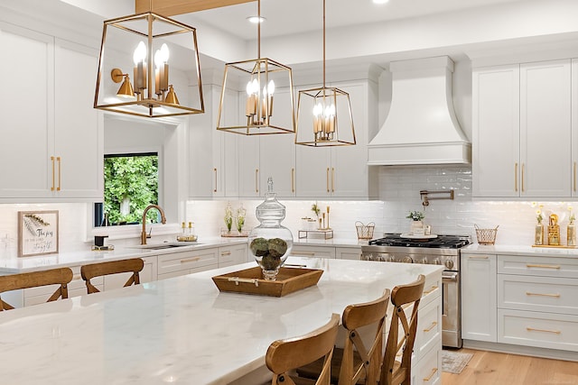 kitchen with decorative light fixtures, sink, high end stainless steel range, and custom exhaust hood