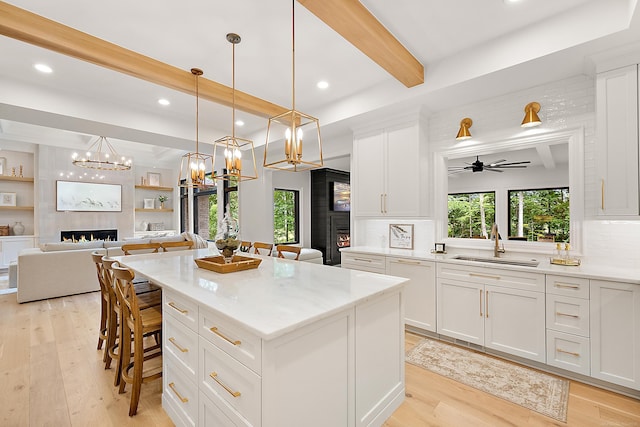 kitchen featuring a kitchen island, white cabinetry, decorative light fixtures, and a large fireplace