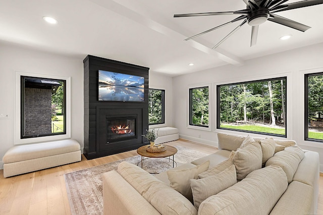 living room with light wood-type flooring, ceiling fan, beam ceiling, and a fireplace