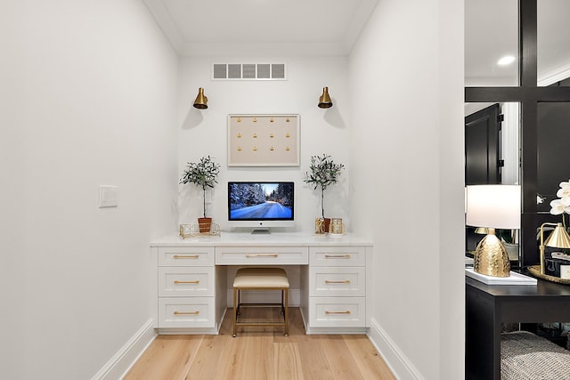 office area with ornamental molding, built in desk, and light wood-type flooring