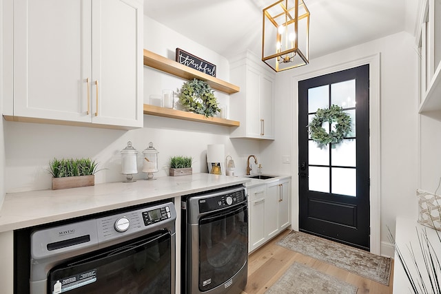 kitchen with hanging light fixtures, sink, white cabinets, light stone countertops, and washer and clothes dryer