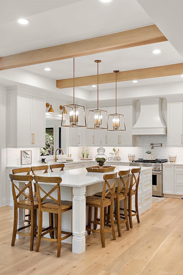 kitchen featuring custom exhaust hood, backsplash, decorative light fixtures, and high end stainless steel range