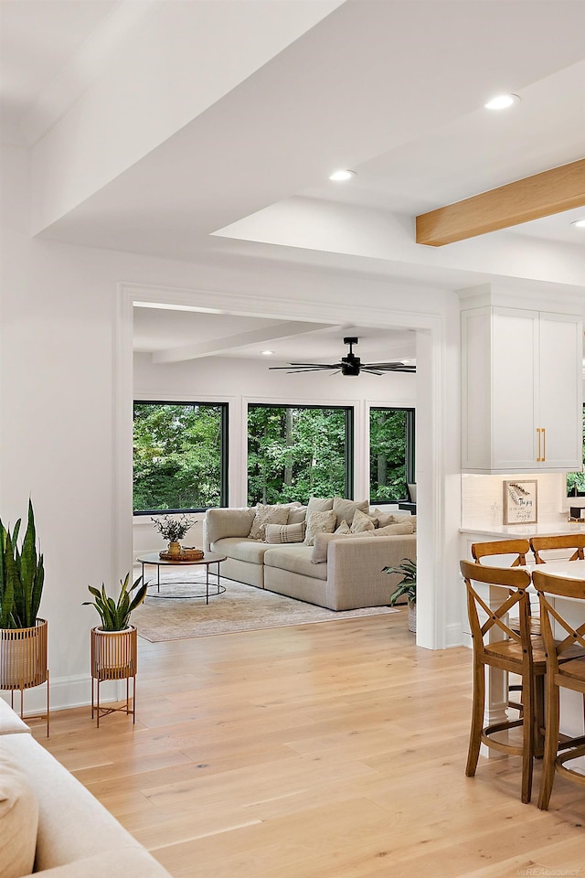 living room featuring ceiling fan, beamed ceiling, and light wood-type flooring