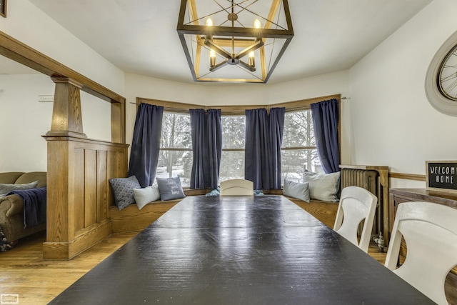 dining space featuring ornate columns, a healthy amount of sunlight, hardwood / wood-style floors, and a chandelier