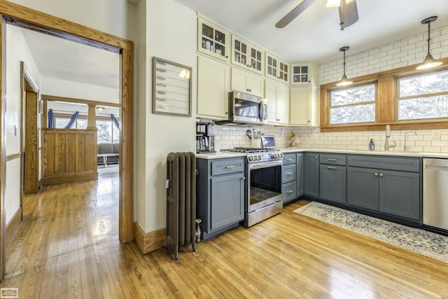 kitchen featuring sink, gray cabinetry, radiator, pendant lighting, and stainless steel appliances