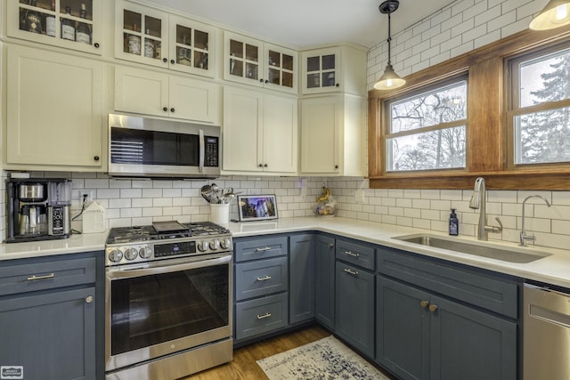 kitchen featuring gray cabinets, appliances with stainless steel finishes, tasteful backsplash, sink, and hanging light fixtures