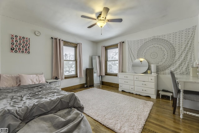 bedroom featuring ceiling fan, radiator heating unit, and dark hardwood / wood-style floors