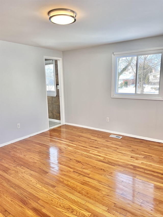 empty room with light hardwood / wood-style flooring and a healthy amount of sunlight