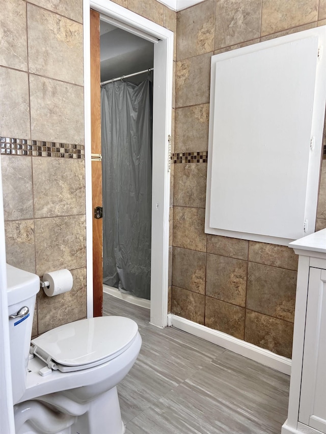 bathroom featuring walk in shower, toilet, tile walls, and hardwood / wood-style flooring