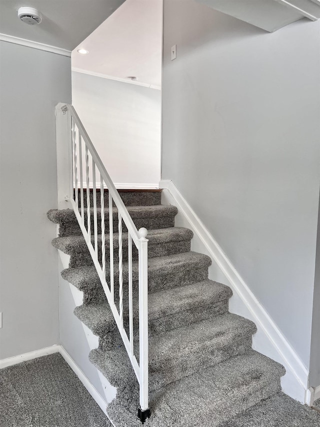 staircase with ornamental molding and carpet