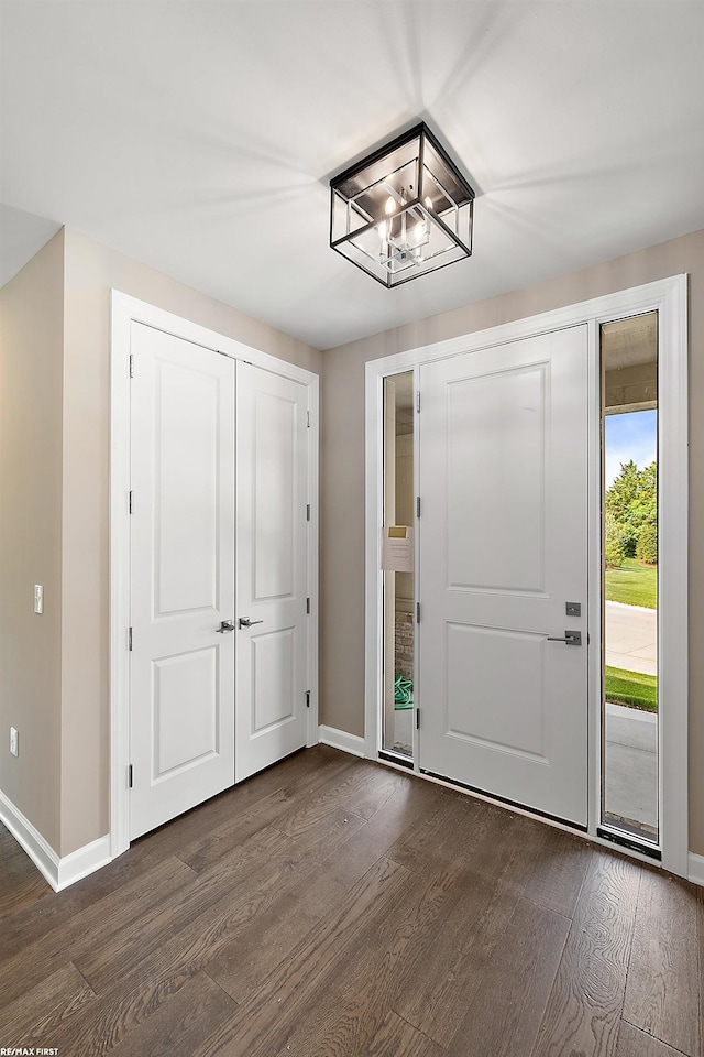 foyer with dark wood-type flooring and an inviting chandelier