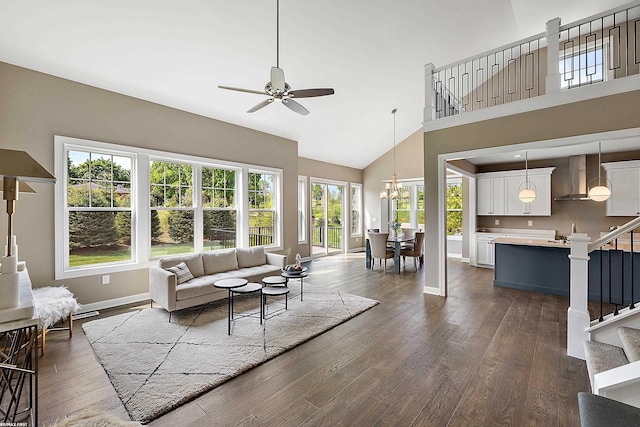 living room with a high ceiling, ceiling fan with notable chandelier, a wealth of natural light, and dark hardwood / wood-style flooring