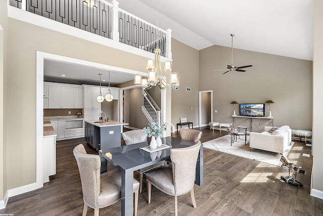 dining area featuring high vaulted ceiling, sink, ceiling fan with notable chandelier, and dark hardwood / wood-style flooring