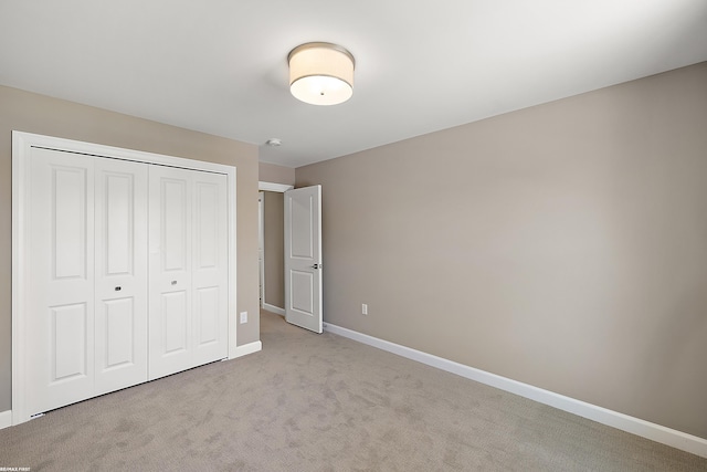 unfurnished bedroom with light colored carpet and a closet