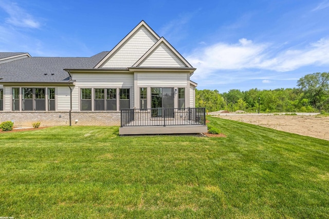 rear view of house with a wooden deck and a lawn