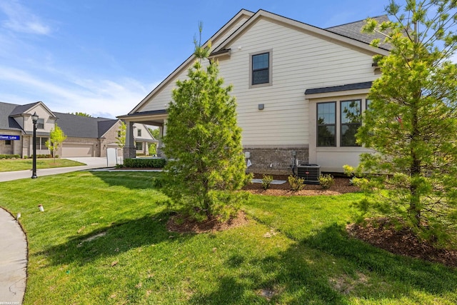 exterior space featuring a garage, a yard, and central AC