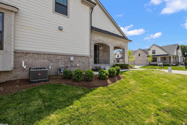 view of home's exterior with a garage, a yard, and central air condition unit