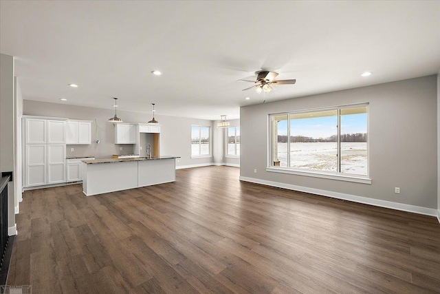 unfurnished living room with sink, dark hardwood / wood-style floors, and ceiling fan