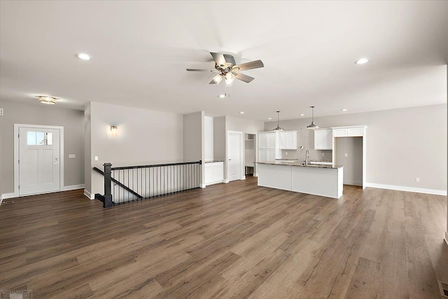 unfurnished living room featuring dark wood-type flooring and ceiling fan