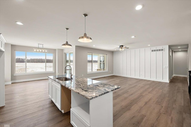 kitchen featuring sink, white cabinetry, stone countertops, decorative light fixtures, and dark hardwood / wood-style flooring