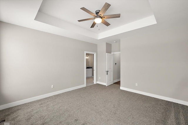 unfurnished bedroom featuring ensuite bath, a raised ceiling, and ceiling fan