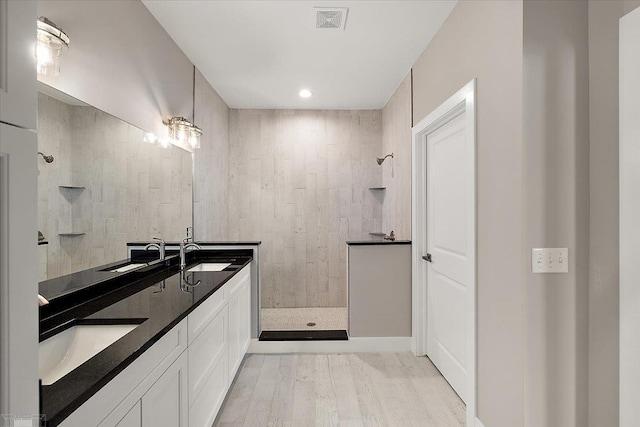 bathroom featuring tiled shower, vanity, and wood-type flooring