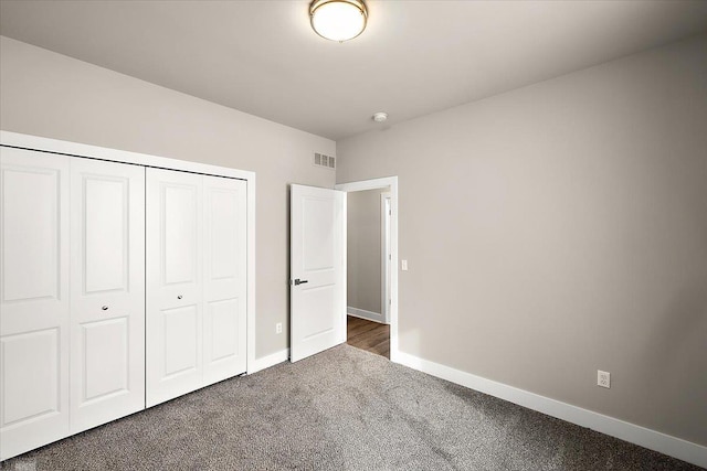 unfurnished bedroom featuring dark carpet and a closet