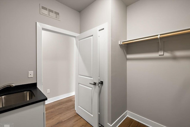 laundry room with hardwood / wood-style flooring and sink