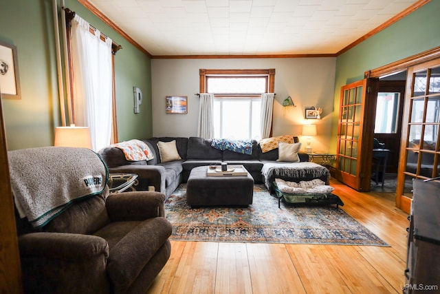 living room featuring wood-type flooring, a healthy amount of sunlight, and crown molding