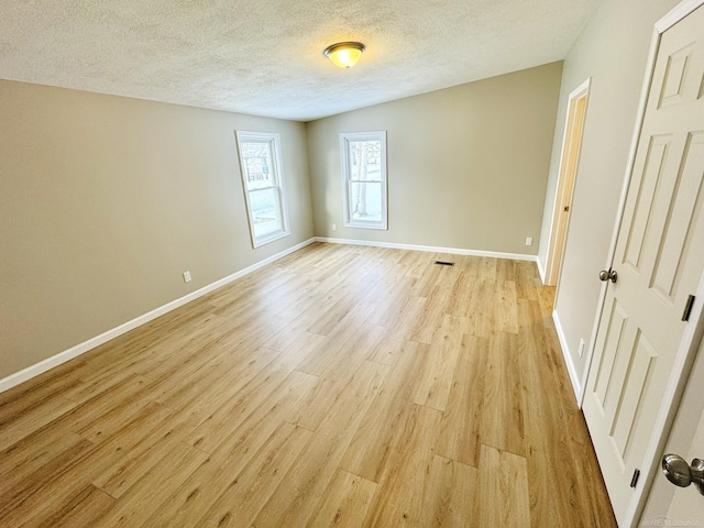 unfurnished room with light hardwood / wood-style floors and a textured ceiling