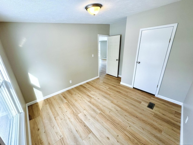 unfurnished bedroom with light hardwood / wood-style flooring, a closet, and a textured ceiling