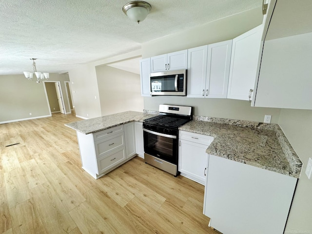 kitchen featuring hanging light fixtures, kitchen peninsula, stainless steel appliances, light stone countertops, and white cabinets