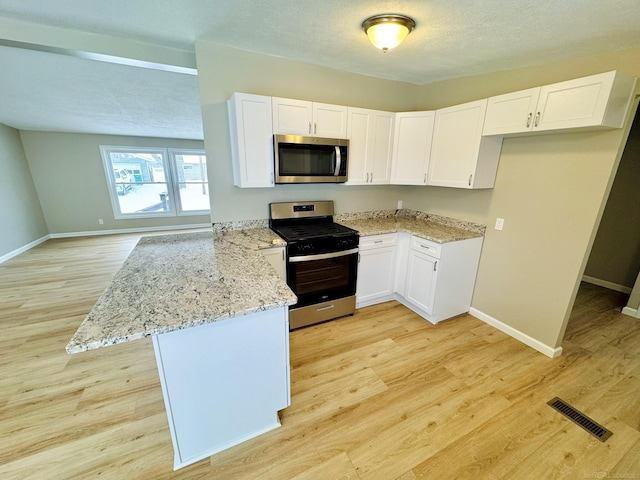 kitchen with white cabinetry, appliances with stainless steel finishes, kitchen peninsula, and light stone counters