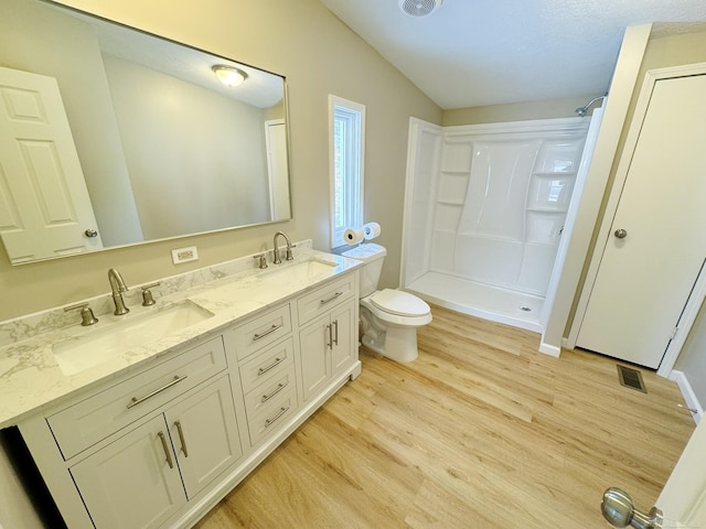 bathroom with lofted ceiling, hardwood / wood-style floors, vanity, a shower, and toilet