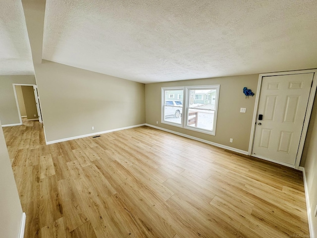 unfurnished living room with light hardwood / wood-style floors and a textured ceiling