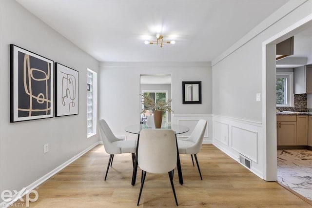 dining space with plenty of natural light, an inviting chandelier, and light hardwood / wood-style flooring