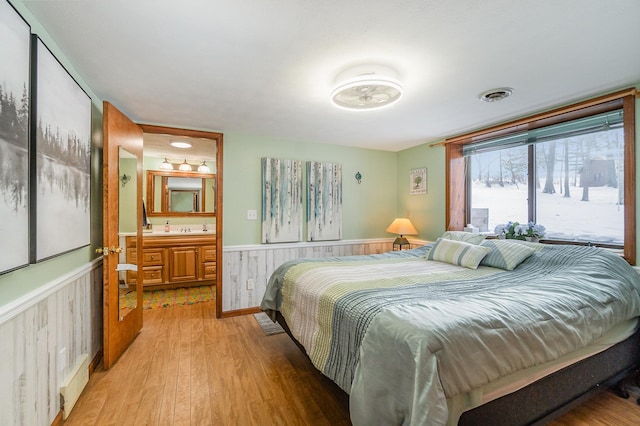 bedroom with ensuite bath and light hardwood / wood-style floors