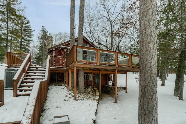 snow covered rear of property with a wooden deck and central AC unit