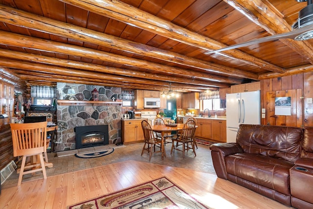 living room featuring sink, beam ceiling, light wood-type flooring, wooden ceiling, and a fireplace