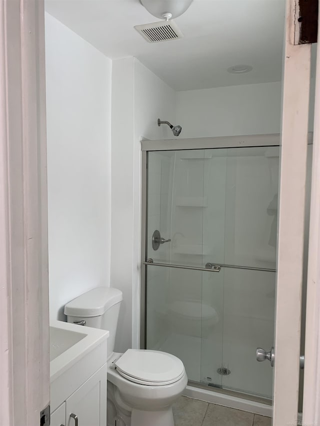 bathroom with vanity, a shower with shower door, tile patterned floors, and toilet