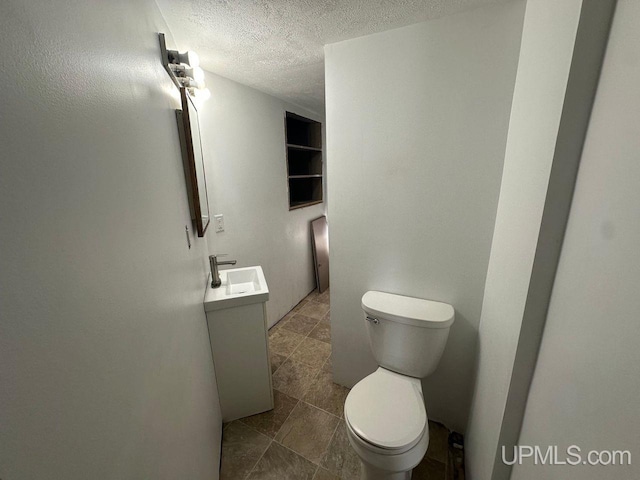 bathroom with vanity, toilet, and a textured ceiling