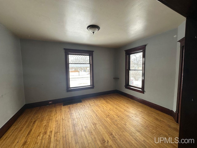 spare room with plenty of natural light and light hardwood / wood-style floors