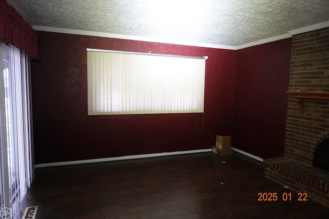 spare room with dark wood-type flooring, ornamental molding, a brick fireplace, and a textured ceiling