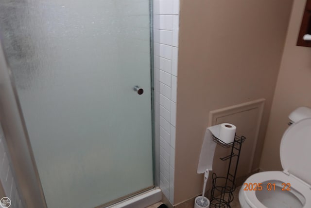 bathroom featuring a shower with shower door and toilet