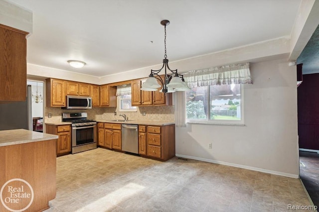 kitchen with pendant lighting, appliances with stainless steel finishes, sink, and decorative backsplash