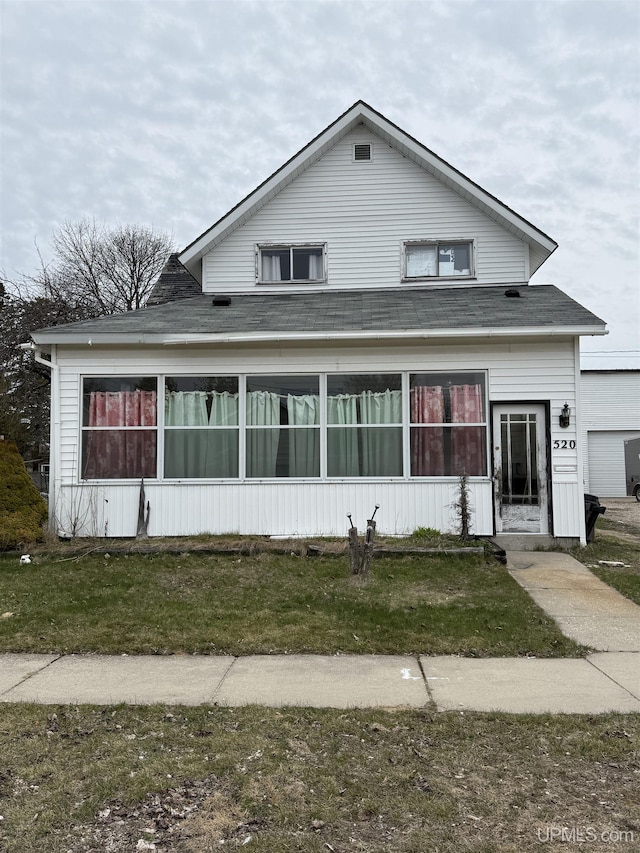 traditional home featuring a front lawn and roof with shingles