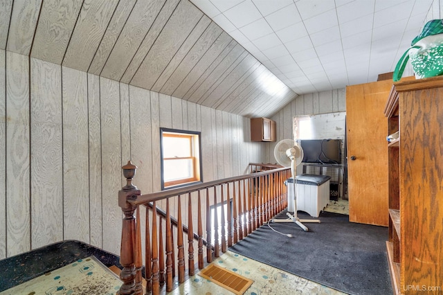 bonus room with vaulted ceiling, carpet flooring, and wood walls